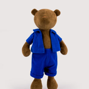 Ours en peluche marron portant une salopette bleue sur fond clair