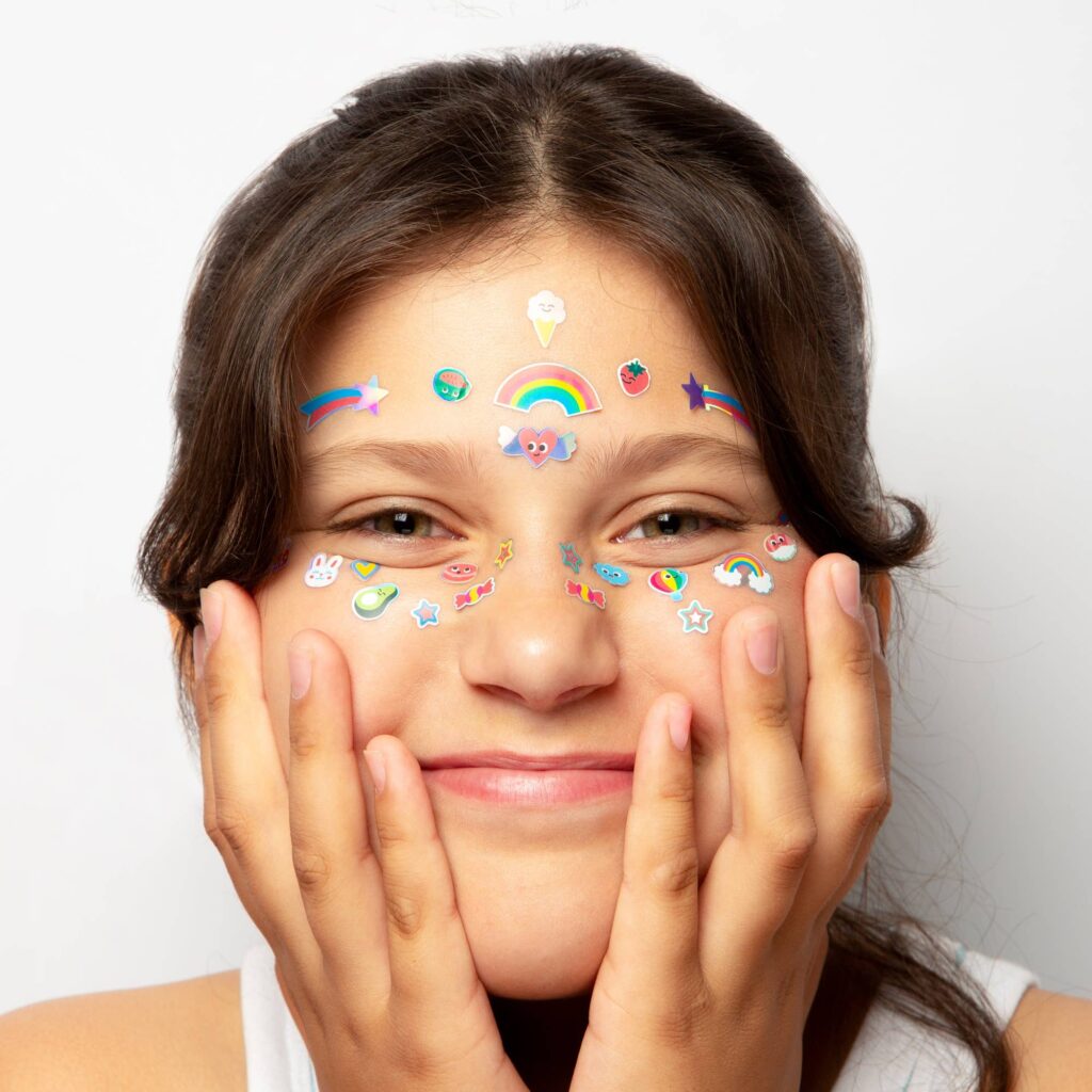 Portrait d’une femme souriante avec des autocollants colorés sur le visage